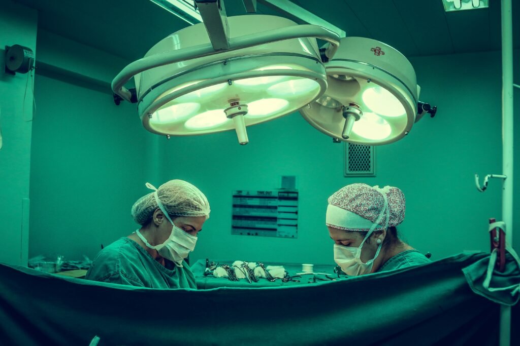 Surgeons in an operating room conducting a medical procedure under bright surgical lights.