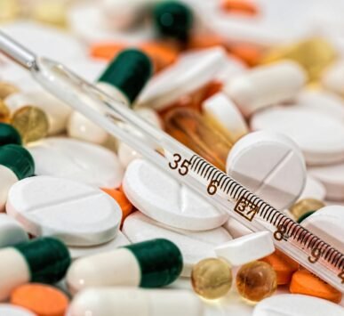 Close-up image showing various pills and a thermometer, emphasizing health and medicine.